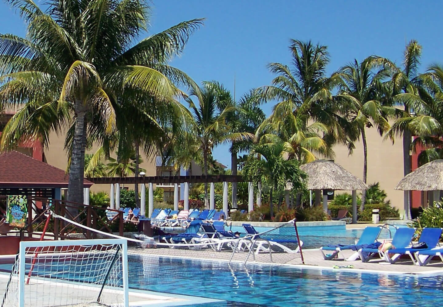 Vacation resort showing a pool and palm trees on a clear sunny day.